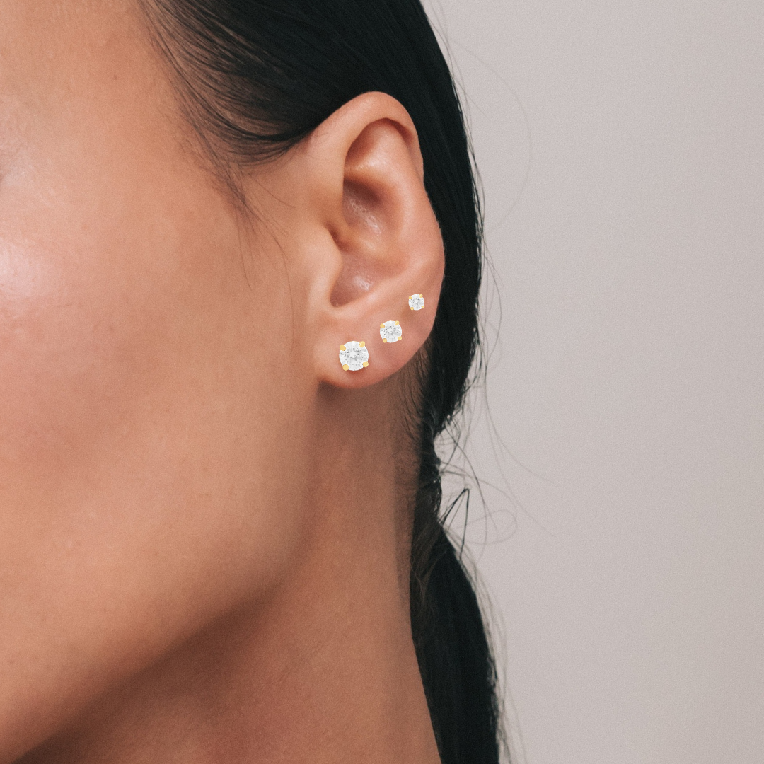 Model wearing two Classic Studs, lab-grown diamond solitaire earrings in yellow gold