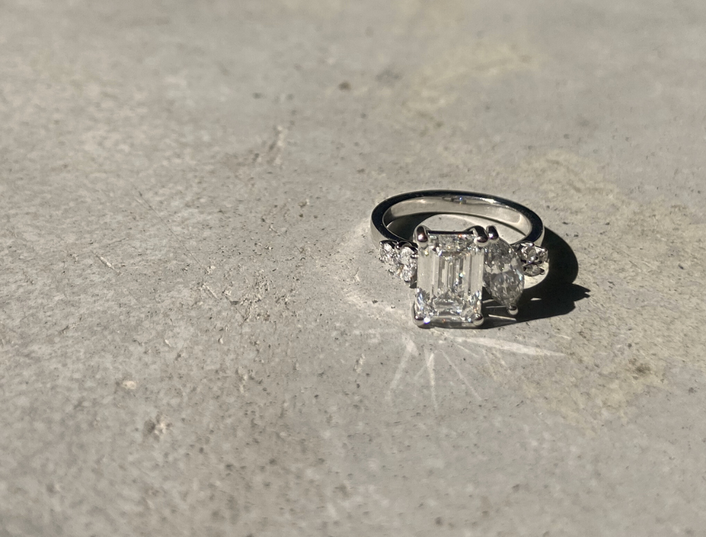 Fine jewelry toi et moi custom design cluster engagement ring in 18k recycled white gold set with emerald cut and marquise cut lab-grown diamonds, shown in close-up