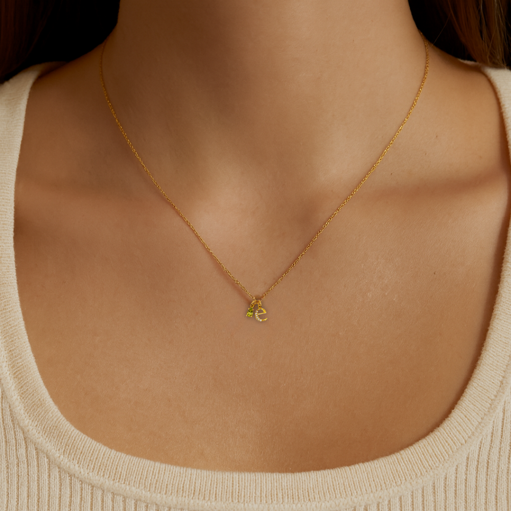 Model wearing the Origins personalised necklace with letter and birthstone charms in recycled 18K yellow gold