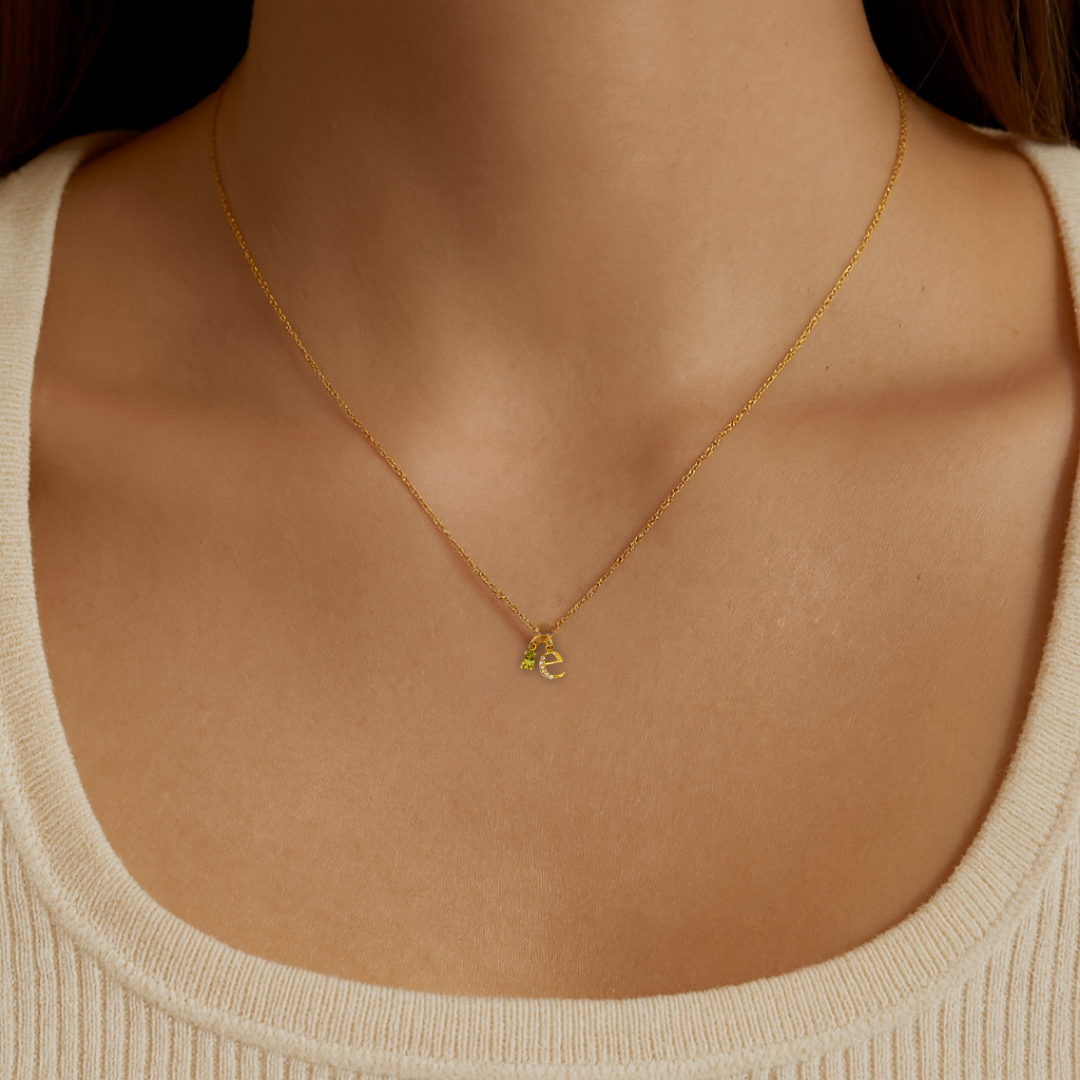 Model wearing the Origins personalised necklace with letter and birthstone charms in recycled 18K yellow gold