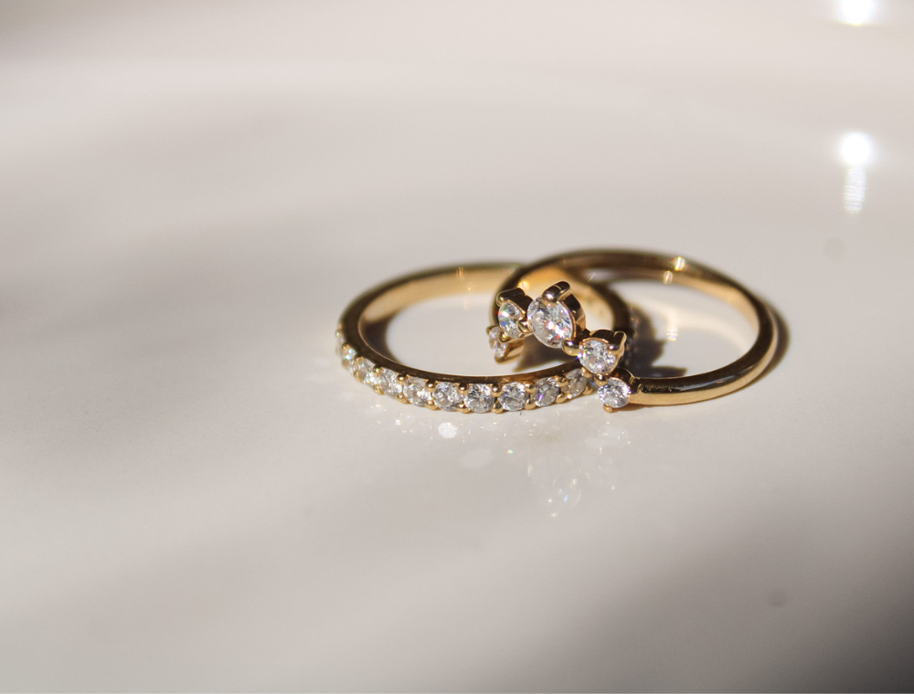 Fine jewelry bridal set — gold diamond engagement ring paired with pavé diamond wedding band photographed on a neutral background.