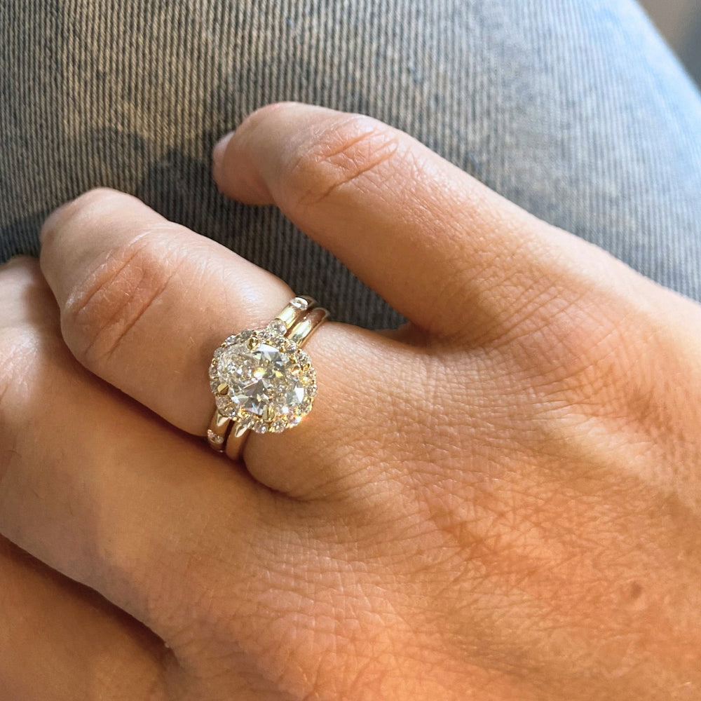 Dahlia Ring worn on the hand with a band, an oval lab-grown diamond in a diamond halo, recycled 18K yellow gold