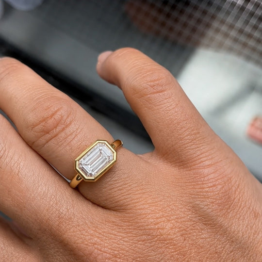 Simone Ring worn on the hand, an emerald-cut lab-grown diamond in a gold bezel, recycled 18K yellow gold