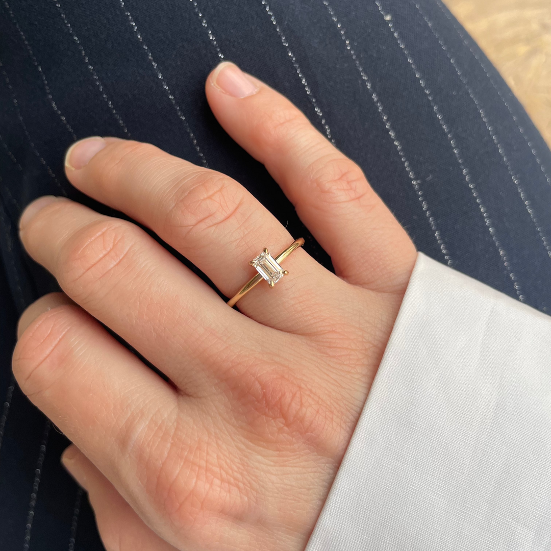 Sustainable emerald lab-grown diamond engagement ring in 18 carat gold worn on hand in Antwerp showroom.