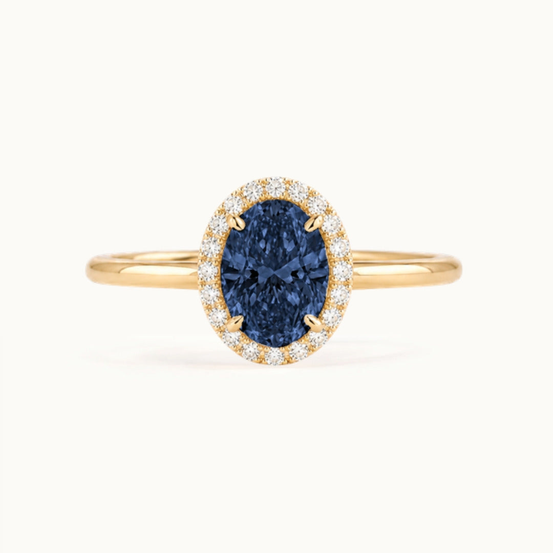 Dahlia Sapphire Ring, an oval blue sapphire in a lab-grown diamond halo, recycled 18K yellow gold