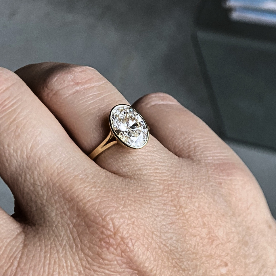 3 carat oval lab-grown diamond in a bezel tulip-basket setting with split shank, worn on the hand, recycled 18K gold, made in Antwerp.