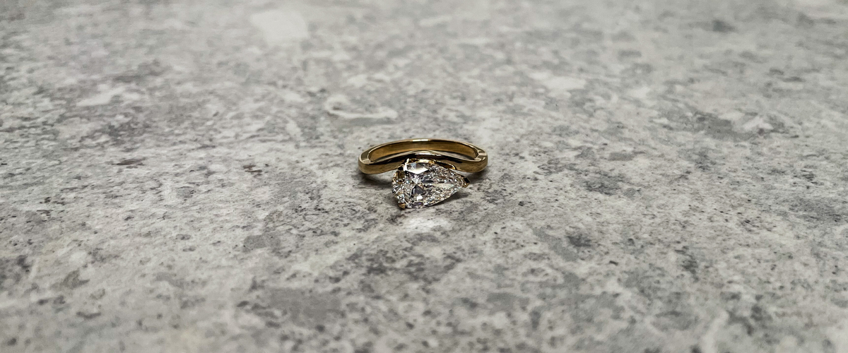 Wavey ring with pear-cut lab-grown diamond engagement ring on a wave band, handmade in recycled 18K gold at Juna Fae Antwerp.