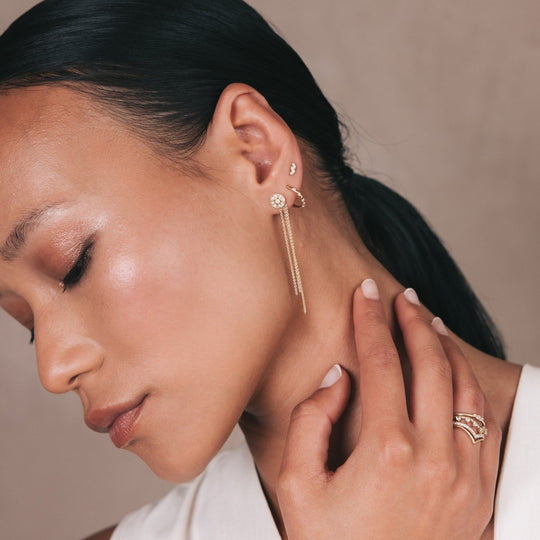 Model styling the Daisy diamond hoop with a gold chain add-on in recycled 18K yellow gold